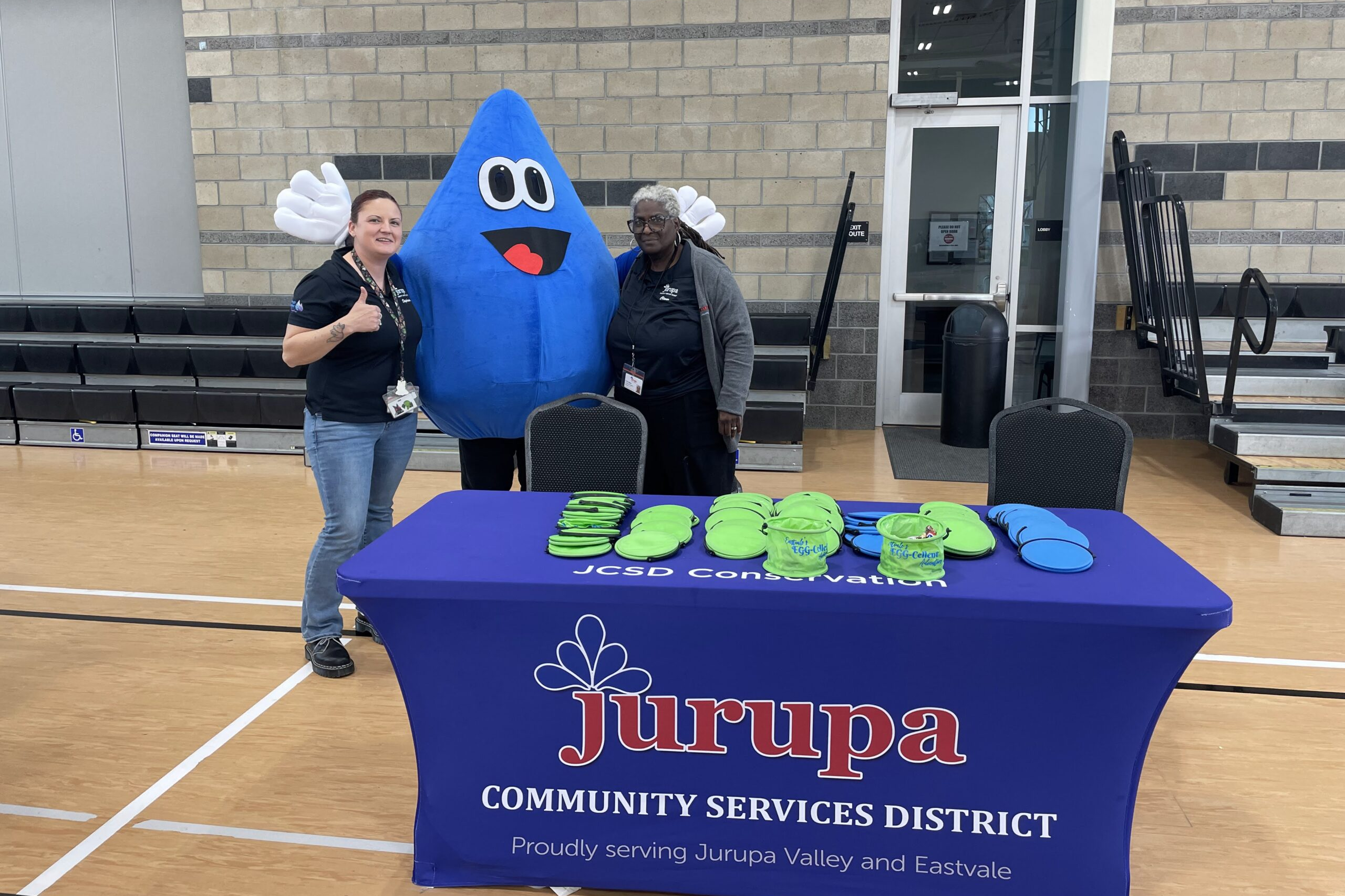 two people with mascot next to JCSD table