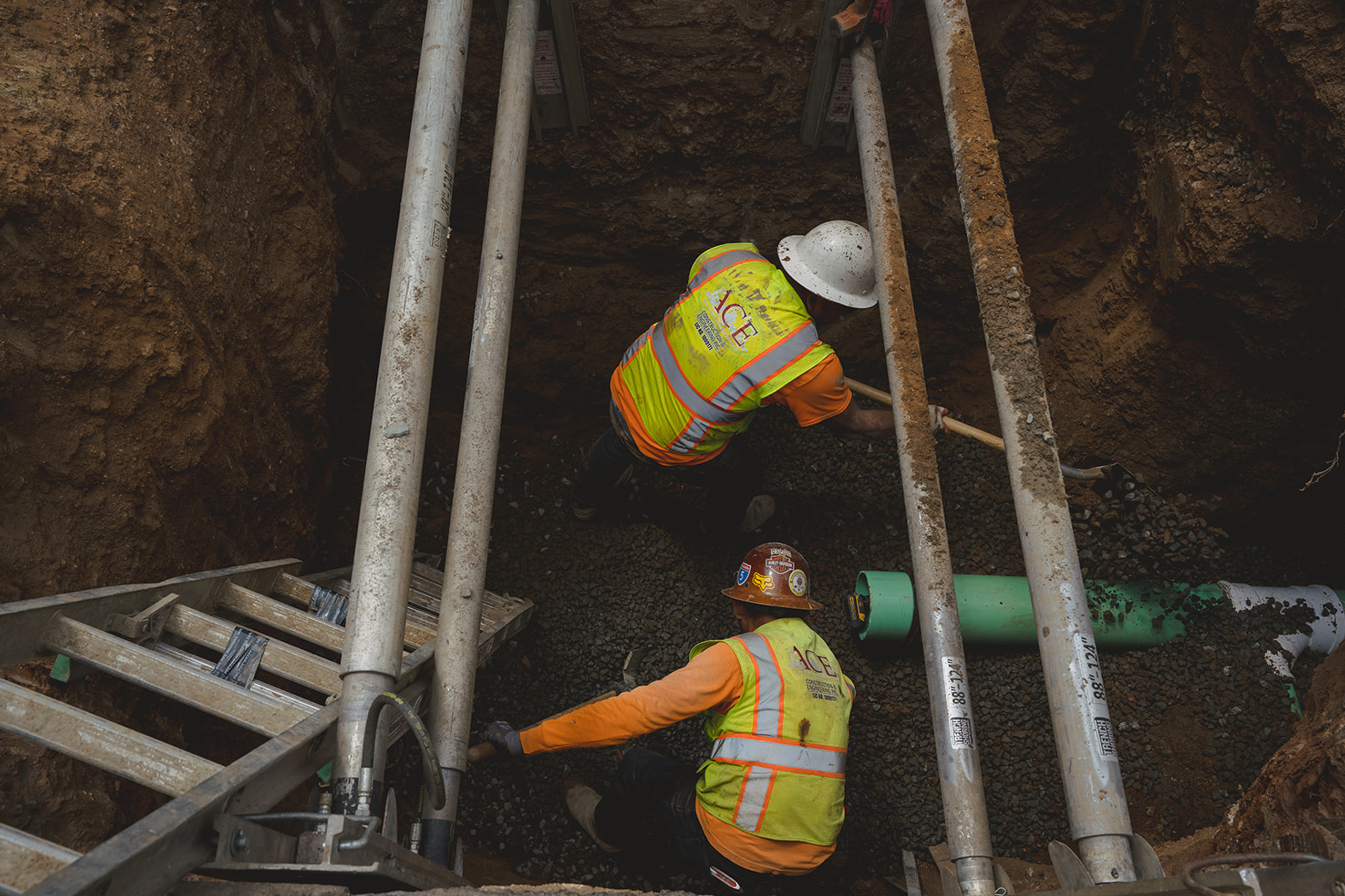 two people working on pipes below ground