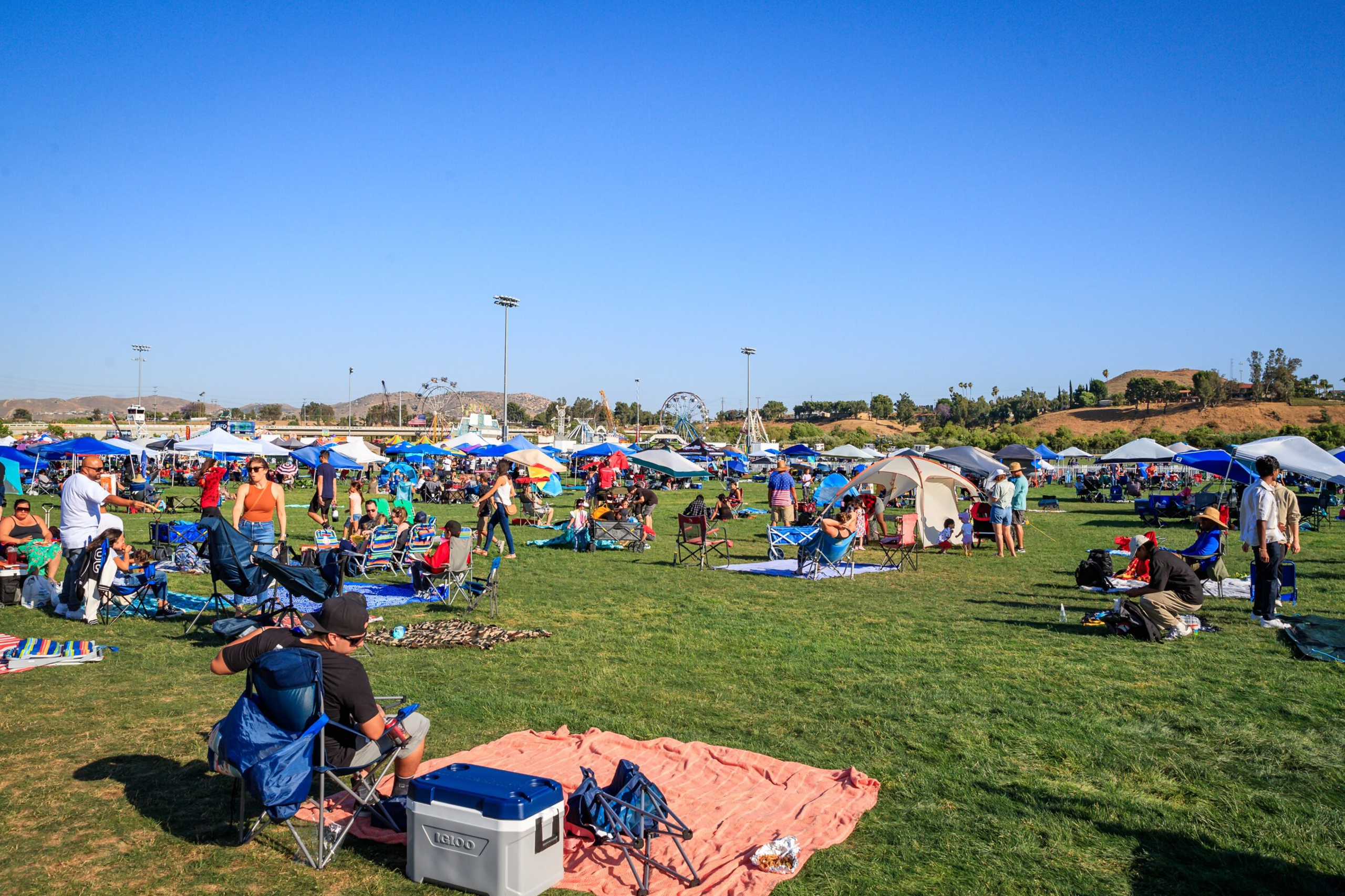 people with tents and picnic blanket in open field